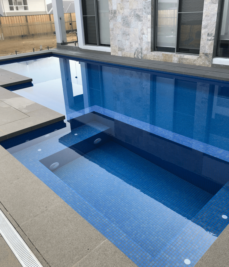 Custom fully tiled swimming pool with sleek blue mosaic tiles by Quasar Pools, experts in Sydney pool renovations and tiling.